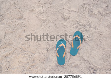 Summer vacation concept. Flip flops on a sandy ocean beach in vintage tone color style, selective focus (detailed close-up shot)