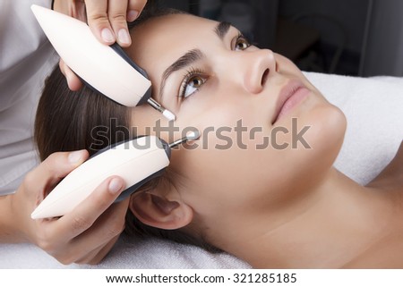 Young pretty woman receiving treatments in beauty salons. Young beautiful dark-haired woman in the office beautician lying on the couch. Miostimulation procedure. Hardware cosmetology.