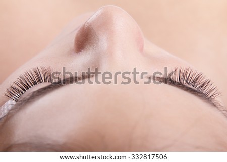 Japanese eyelash extensions. Long eyelashes. Beautiful dark-haired girl lies on a couch in the office of the master eyelash. View from the forehead .