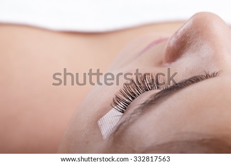 Japanese eyelash extensions. Long eyelashes. Beautiful dark-haired girl lies on a couch in the office of the master eyelash. View from the forehead .