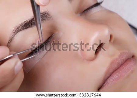 Japanese eyelash extensions. Long eyelashes. Beautiful dark-haired girl lies on a couch in the office of the master eyelash.