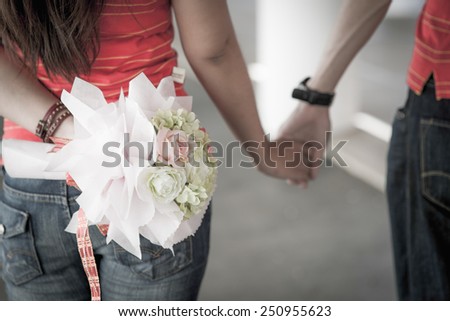 Loving couple is walking together and holding hands with bouquet