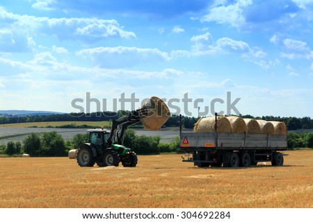 Tractor collecting hay bales in the fields