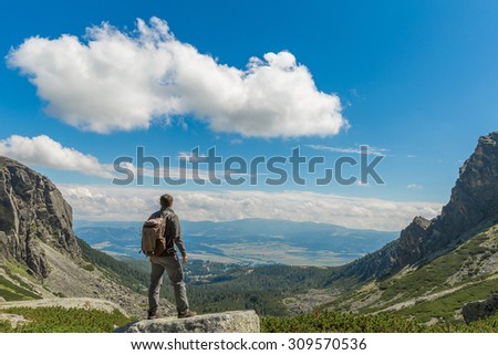 A traveler with a backpack standing on a mountain peak.