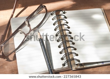 Empty pages of a notebook on a desk. Pencil and glasses on the notebook. Space for copy.