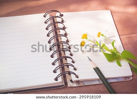 Empty page of notebook on desk, Black pencil and flower on notebook, Space for text, Vintage style