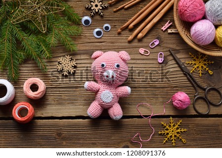 Pink pig, symbol of 2019. Happy New Year. Crochet toy for child. On table threads, needles, hook, cotton yarn. Handmade crafts on holiday with your own hands. DIY concept.