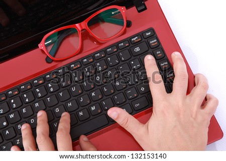 hands typing a red notebook with a glasses a sign of labor and technology