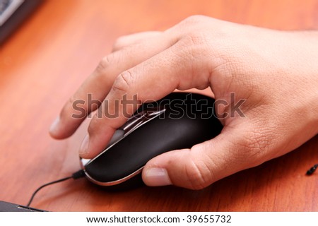 Hand using the computer mouse on a wooden surface