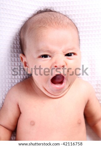 Baby yawn over white blanket. Head and shoulders portrait