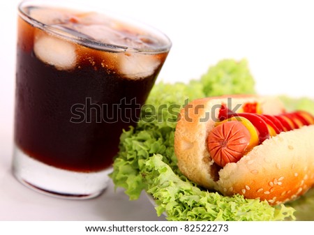 black drink and hot dog over lettuce over white background