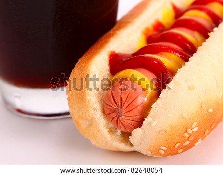 black drink and hot dog over lettuce over white background