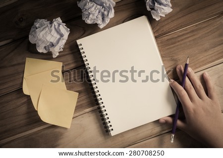 Hand-written note in pencil on a wooden table - hand focus