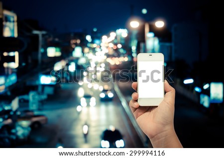 Mobile smart phone behind a blur of traffic.