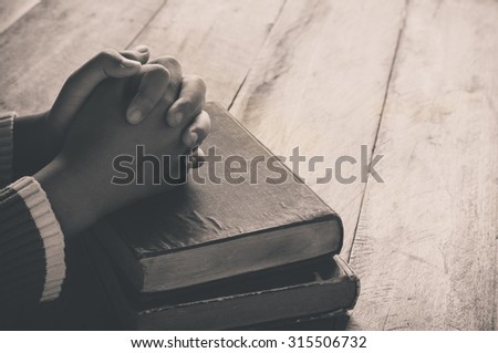 Hands with Bible on wood table tone sepia