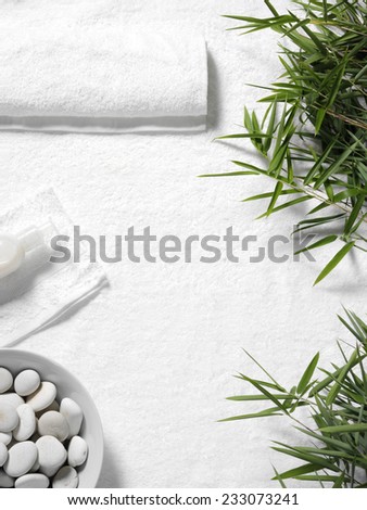 Bamboo leaves and a white towel for massage, with Cream and pebbles on a white towel background. Copy space for a health and leisure business.