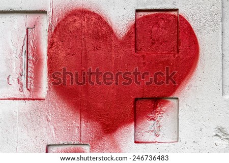 A red heart painted with love on a wall.