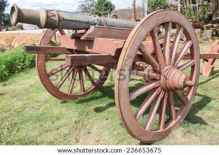Old bomb on wooden wheel standing on green grass for war weapon background
