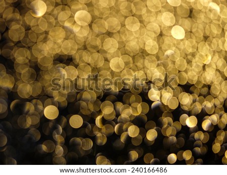 Defocused golden bokeh glowing in the dark for holiday and celebration blurred night background