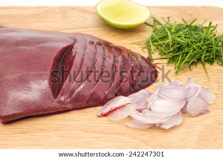 Fresh and raw pig\'s liver with sour lime, red onion and kaffir lime on chopping block, ready for cooking