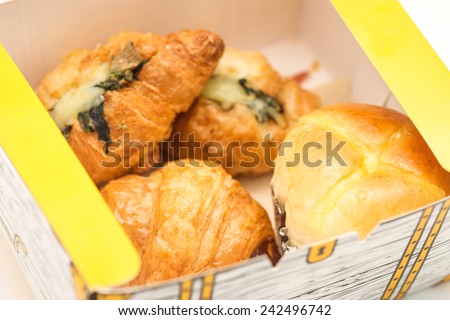 Close up of delicious and fresh baked croissant and soft bun in a paper box for take away breakfast