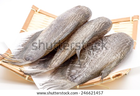 Fresh and raw salted fish on bamboo basket on white background