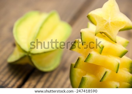 Sweet and sour star fruits or carambola cut in pieces on brown wood for tropical food background