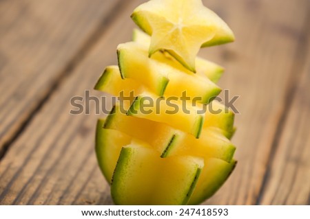 Sweet and sour star fruits or carambola cut in pieces on brown wood for tropical food background