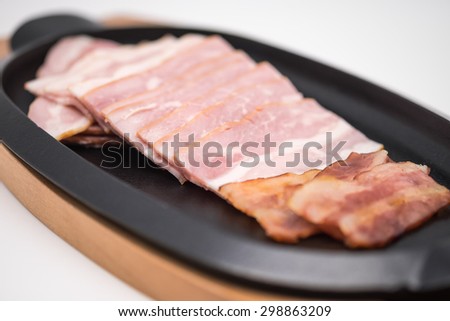 Fresh raw and grilled bacon or pork belly on black metal plate for breakfast with white background