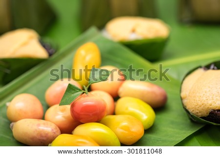 Fresh and delicious colorful bean in fruit shape on green banana leaf for local Thai dessert background