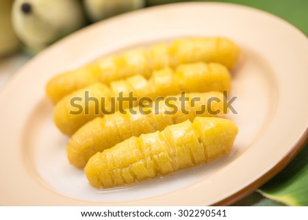 Fresh and sweet yellow banana with coconut milk on banana leaf for local Thai dessert background
