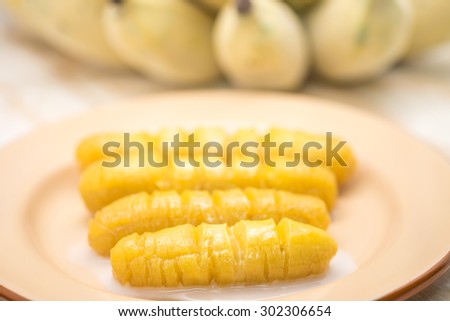 Fresh and delicious bright yellow banana on brown metal plate with coconut milk for local Thai sweet dessert background