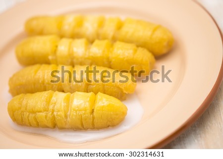 Close up of fresh and sweet yellow banana on brown metal plate on wood texture for Thai dessert background