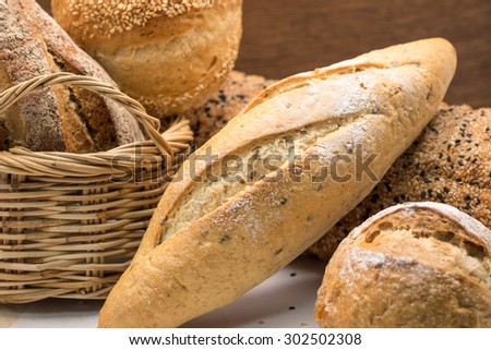 Freshly baked whole wheat bread and roll in bamboo basket on wood for healthy diet background