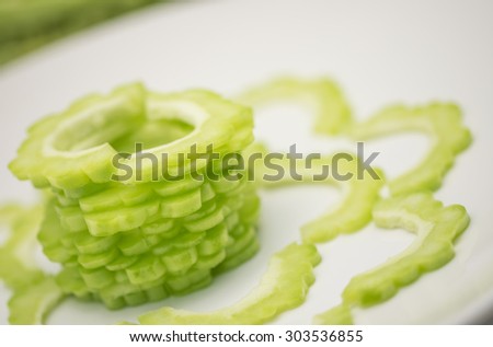 Fresh and sliced raw green bitter gourd on white ceramic plate for food ingredient background