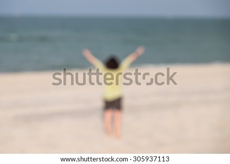 De focused or blurred image of a lady raising hands on the beach, symbol of freedom with nature background