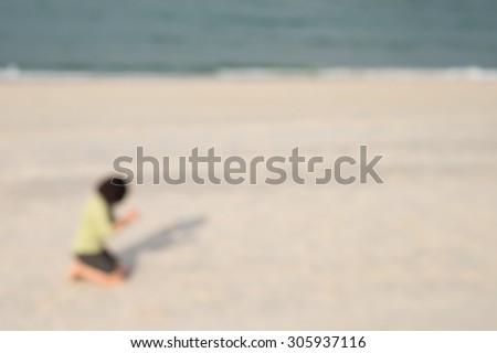 De focused or blurred image of a lady kneeling down to pray and worship on the beach along the seashore