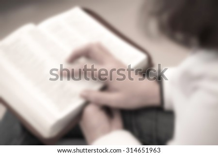 De focused or blurred image of a woman reading the holy bible in the church for religion background