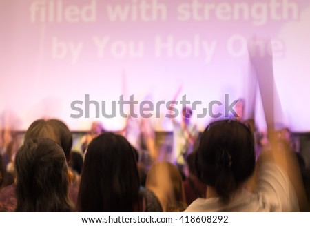 Blurred image of people raising hands in surrendering gesture for religion background