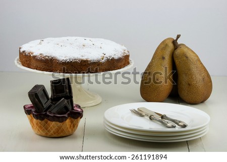 Italian cake with ricotta, pears and drops of chocolate on white and wooden table.