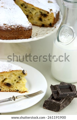 Italian cake with ricotta, pears and drops of chocolate on white and wooden table.
