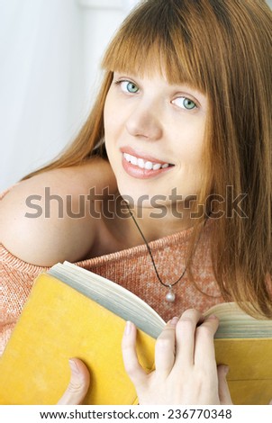 Young beautiful girl holding an old yellow book