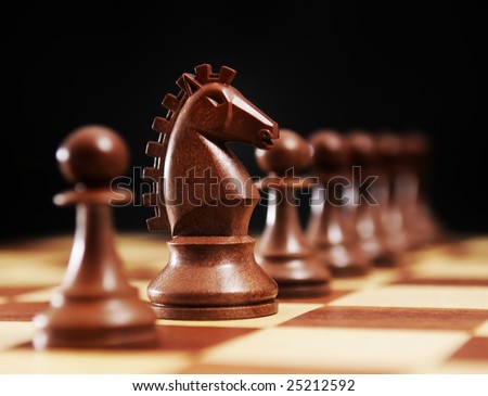Chess - horse and black pawns on a chessboard and black background