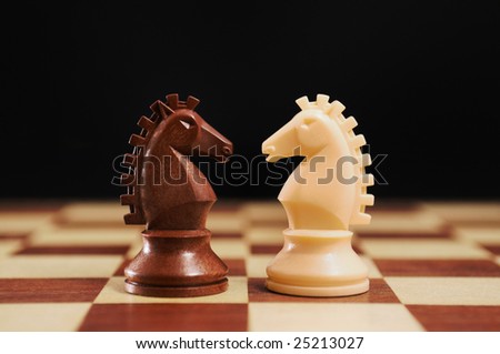 Chess - black and white horses on a chessboard and black background