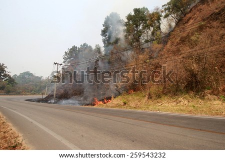 Wild fire road in Muang District of unknown origin to create air pollution and our vision of driving a car is not visible to the eye, nose, and heartburn clear on 10 March 2015
