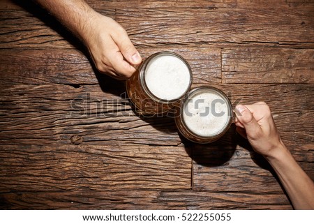 Male hands with beer mug on an old wooden table