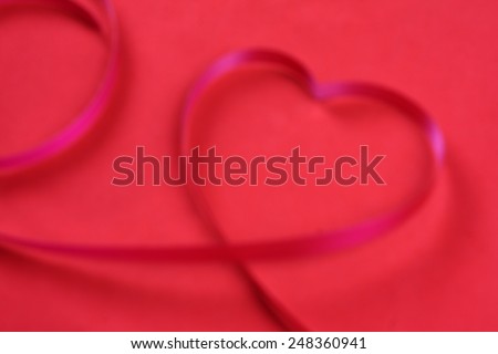 Pink heart ribbon on red background:out of focus
