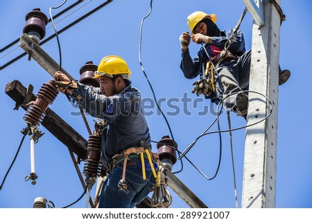 Bangkok, Thailand - May 16, 2015:  Electricians working together to replace the electrical insulator on the electricity pole