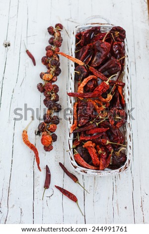 Overhead view of colorful dried ground peppers  in basket spilling onto an old aged scored wooden surface in a country kitchen with a vintage sieve. Color brand