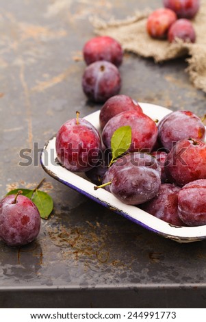 Fresh plums on a metal old plate. Healthy food from garden. Food blue background.